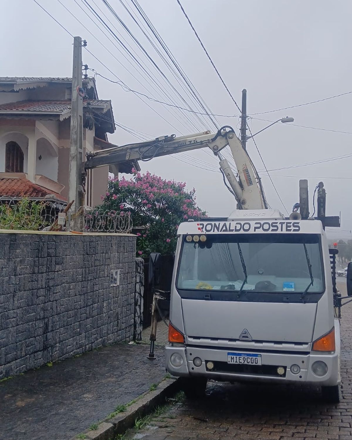 Caminhão munck da Ronaldo Postes posicionando poste em rua residencial