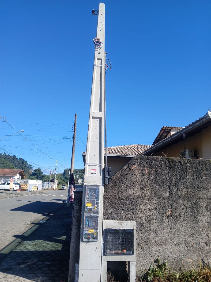 Poste padrão com caixas e mureta em rua de bairro